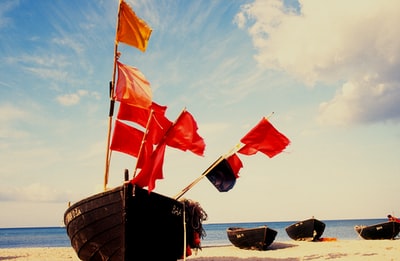 白天，棕色木船上悬挂红旗和白旗